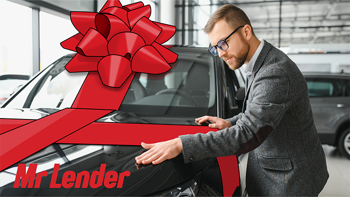 A car dealer positioning a big red bow on a brand new car