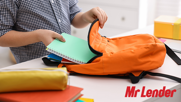 A child is placing their books in their backpack ready for school